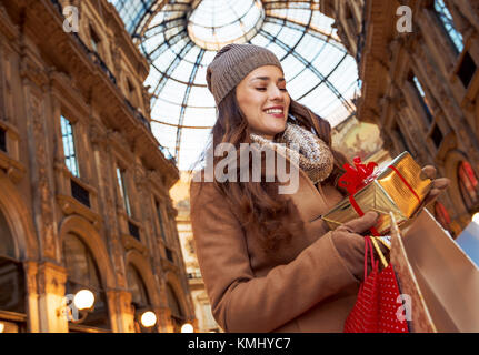 Sur une énorme vente de Noël dans la capitale de la mode italienne moderne. smiling woman with shopping bags in Galleria Vittorio Emanuele II à Milan, Italie recherche Banque D'Images