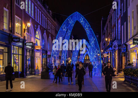 Personnes marchant le long de South Molton St à l'heure de Noël, qui a été décoré avec de grandes arches de Noël bleues, Londres, Royaume-Uni Banque D'Images