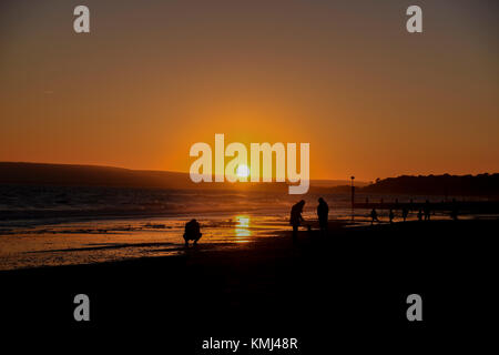 Femme et chien sur la plage au coucher du soleil en Silhouette Banque D'Images