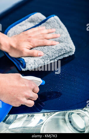 Close-up of male hands avec voiture nettoyage produit de nettoyage en microfibre et lavage de voiture à l'extérieur à l'essuie-tout Banque D'Images