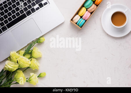 24 avec blanc macarons colorés, fleurs, ordinateur portable, portable et tasse de café Banque D'Images