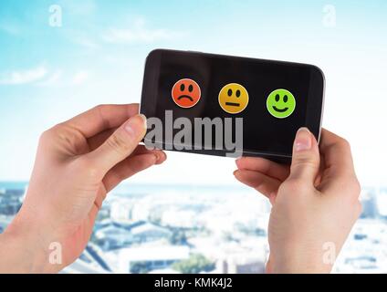 Digital composite of Hand holding phone avec satisfaction smiley icones d'information Banque D'Images