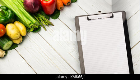 Le bloc-notes noir contre ligne de légumes sur la table Banque D'Images
