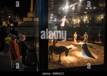 Les enfants regardent une maquette d'une scène de la nativité à Trafalgar Square après sa les lumières d'arbre de Noël ont été mis en marche ce soir. Banque D'Images