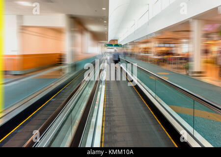 Tapis roulant moderne-vitesse de marche pour les passagers à l'aéroport avec flou de vitesse silhouettes de personnes Banque D'Images