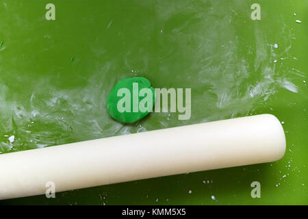 Gâteau fondant et vert sur un rouleau à pâtisserie vert mat Banque D'Images