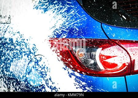 Vue arrière du SUV compact bleu sport voiture avec un design moderne et de se laver avec du savon. Location de couverts de mousse blanche. Car care service business concept. Banque D'Images