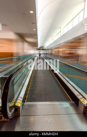 Tapis roulant moderne-vitesse de marche pour les passagers à l'aéroport avec flou de vitesse silhouettes de personnes Banque D'Images