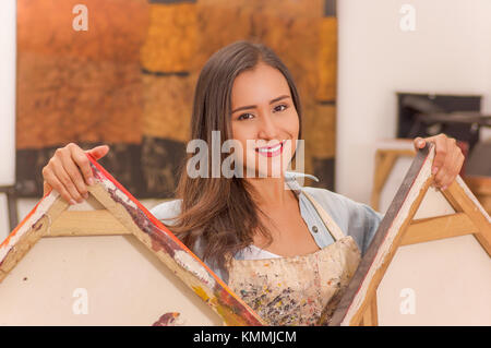 Beautiful smiling woman painter tenant dans ses mains un cadre vide dans un contexte de la peinture studio, des cours d'art pour les adultes, l'éducation concept Banque D'Images