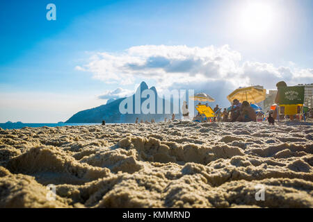 Rio de Janeiro - mars 06, 2016 : se détendre sur la plage d'Ipanema contre l'emblématique silhouette de deux frères montagne dans l'arrière-plan. Banque D'Images