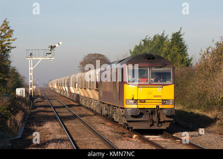 Un certain nombre de locomotives diesel de catégorie 60 60002 un groupe de travail chargé de passage de pierre le sémaphore des signaux à Manea dans Cambridgeshire. Banque D'Images