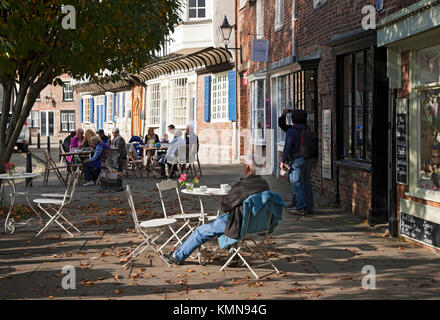 Les personnes assises à l'extérieur aux tables de café sur le trottoir extérieur dans le centre-ville York North Yorkshire Angleterre Royaume-Uni Grande-Bretagne Banque D'Images