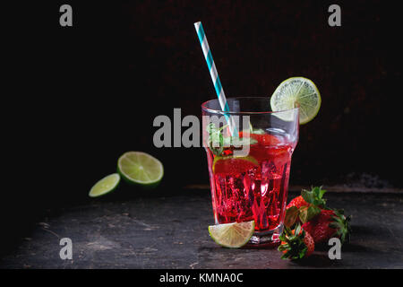 Verre à cocktail rétro avec tubes limonade aux fraises fait maison, servi avec des fraises fraîches, menthe, citron vert et des glaçons overdark arrière-plan. Voir s Banque D'Images