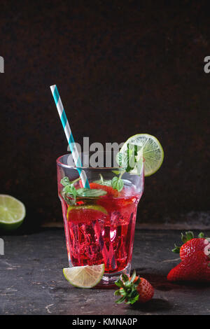 Verre à cocktail rétro avec tubes limonade aux fraises fait maison, servi avec des fraises fraîches, menthe, citron vert et des glaçons overdark arrière-plan. Voir s Banque D'Images