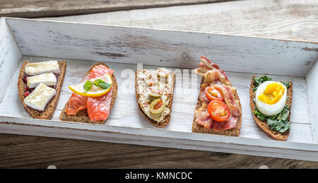 Bruschetta avec garnitures différentes sur le plateau en bois Banque D'Images