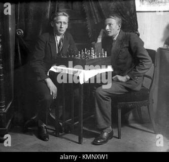 C1930 deux jeunes hommes posent tout en jouant un jeu d'échecs. photo par Tony henshaw Banque D'Images