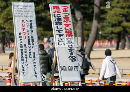 Les visiteurs passent devant des panneaux de mise en garde exposés devant le Palais impérial le 9 décembre 2017, à Tokyo, au Japon. Le Palais impérial ouvre ses portes au public deux fois par an pendant la saison de floraison des cerisiers et de feuillage d'automne. Selon l’Agence impériale des ménages, environ 21 000 personnes ont visité la route de 750 mètres entre la porte Sakashita et la porte Inui lors de son premier jour d’ouverture le 2 décembre. La rue Inui reste ouverte au public jusqu'au 10 décembre. Crédit : Rodrigo Reyes Marin/AFLO/Alamy Live News Banque D'Images