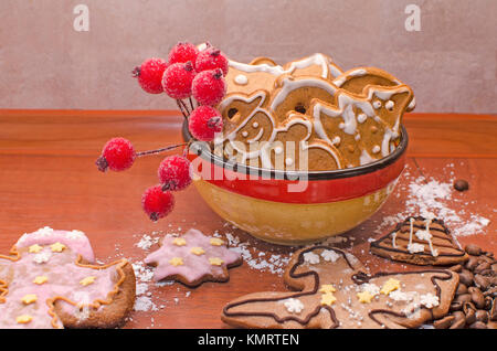 Un bol plein de pains de Noël avec glaçage blanc, les grains de café et Rowan twig pour décoration sur une planche en bois Banque D'Images