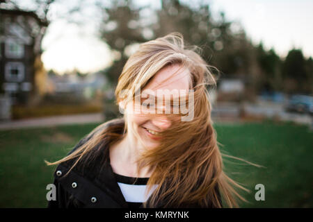 Cheerful woman tossing cheveux à park Banque D'Images