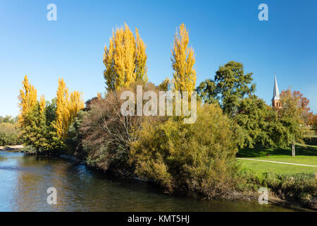 Vue sur la rivière Tumut et les peupliers d'or rayonnant à l'église anglicane All Saints à Tumut dans les montagnes enneigées de la Nouvelle Galles du Sud. Banque D'Images