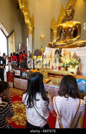 Bangkok, Thaïlande. Les fidèles prient avant le Bouddha d'or au Wat Traimit Temple tandis que les touristes se mêlent dans l'arrière-plan. Le bouddha est assis en th Banque D'Images