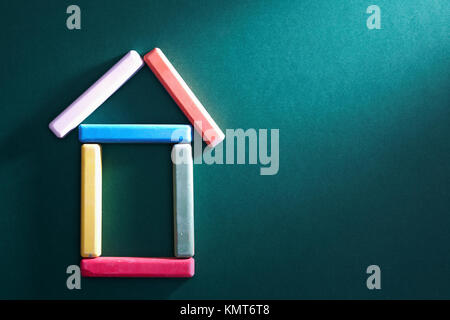 Close-up des bouts de craie de couleur mis en forme de maison sur tableau noir Banque D'Images