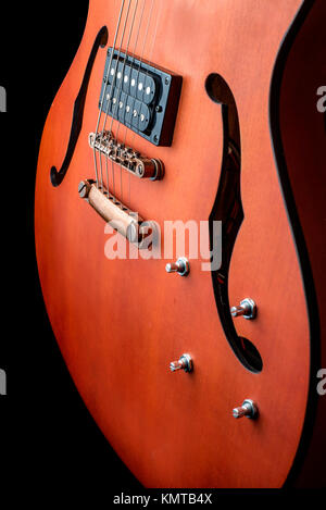 Guitare électrique corps creux avec humbuckers. Macro shot, fond noir, dark key Banque D'Images