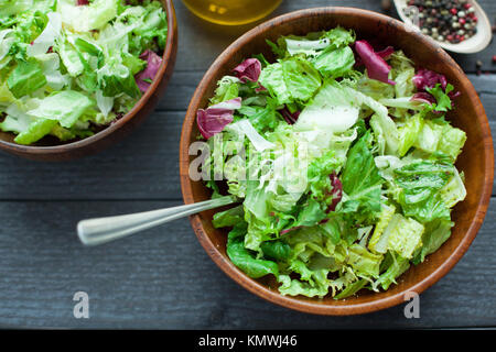 Une assiette de salade fraîche frisse, Romano et radiccio avec de l'huile d'olive, sel et percec dans un bol en bois. Vue d'en haut. Banque D'Images