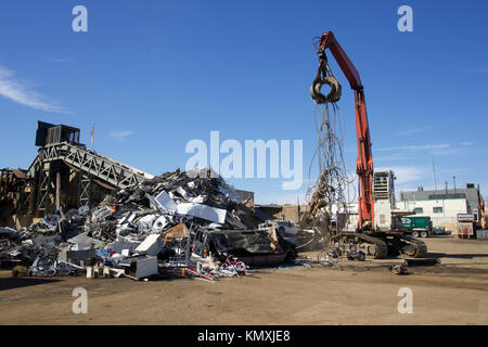 Centre de recyclage avec les balles de métal et de grue avec claw tossing camion et roues rouillées Banque D'Images