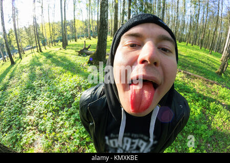 Les jeunes hommes drôles montre sa langue objectif fisheye. Banque D'Images