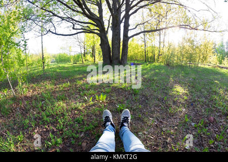 Femme jambes dans sneaker. jeter sur l'herbe verte Banque D'Images