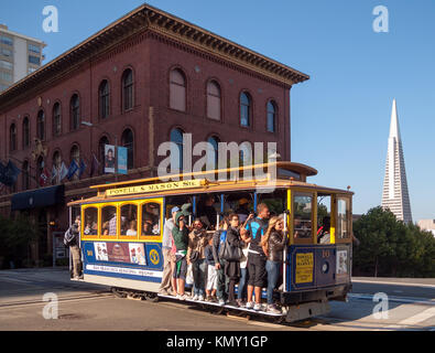 La Powell-Mason Cable Car (ligne 59) sur Nob Hill avec l'University Club of San Francisco et la Transamerica Pyramid en arrière-plan. Banque D'Images