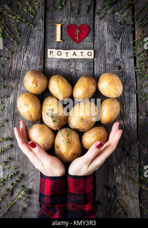 Femme tenant au thym Pommes de terre sur fond de bois rustique de la vue supérieure Banque D'Images