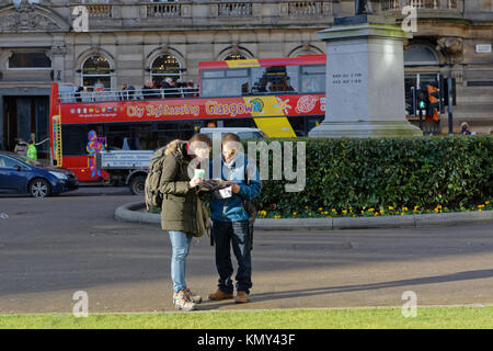 Les touristes étrangers backpackers city bus de tourisme glasgow reading map garçon fille couple George Square, Glasgow La ville de Glasgow, Royaume-Uni Banque D'Images