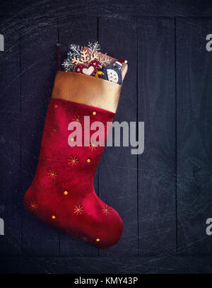 Bas avec rouge présente et les jouets de Noël sur fond de bois Banque D'Images