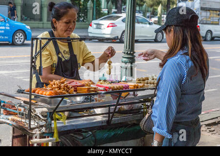 Bangkok, Thaïlande. Street Food Vendor offrant des brochettes, hot-dogs, viandes grillées. Banque D'Images