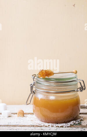 Pot de sauce au caramel fait maison, servi avec des morceaux de sucre sur la table en bois Banque D'Images