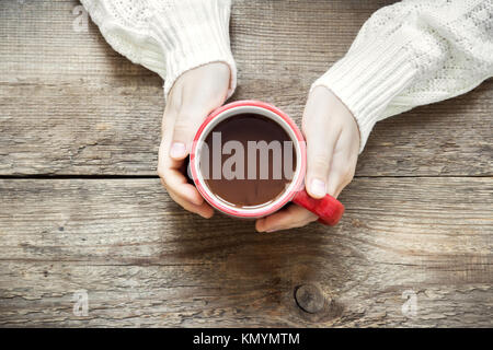 Les mains tenant la tasse de chocolat chaud (café) sur fond de bois rustique with copy space Banque D'Images