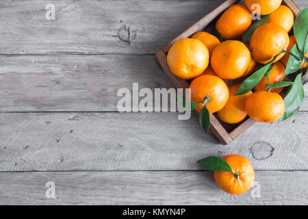 Tangerines (oranges, clémentines, agrumes) avec des feuilles vertes sur fond de bois with copy space Banque D'Images