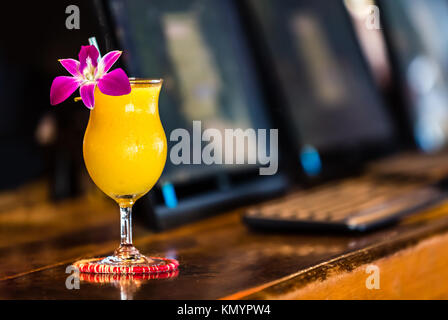 Cocktail jaune avec orchidée fleur dans le bar du fond flou Banque D'Images