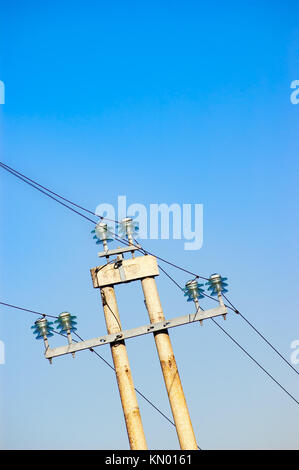 Ligne électrique avec les fils fixés sur les isolateurs sur un haut pylône contre ciel bleu clair Banque D'Images