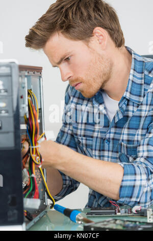 Handsome computer engineer repairing un pc défectueux Banque D'Images