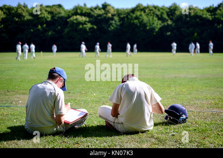 Deux jeunes garçons marquer un match de cricket Banque D'Images