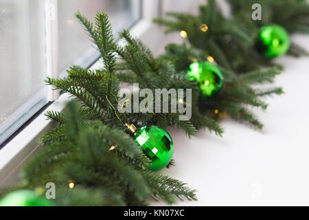Fenêtre blanche-sill décorées avec des branches vertes de vacances arbre et boules de fête. Libre de Noël à manger. Image couleur horizontal. Banque D'Images