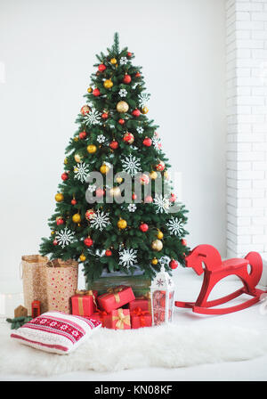 Beau vert sapin de Noël magnifiquement décoré pour la fête. Nombre de boîtes enveloppées dans du papier de fête rouge dans le cadre de branches de pin. Couleur Vertical p Banque D'Images