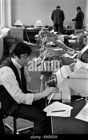 Machine à ruban adhésif pour employés de bureau. Lieu de travail années 1970 Royaume-Uni hommes travaillant dans un bureau années 70 Londres Angleterre 1972 Royaume-Uni HOMER SYKES Banque D'Images