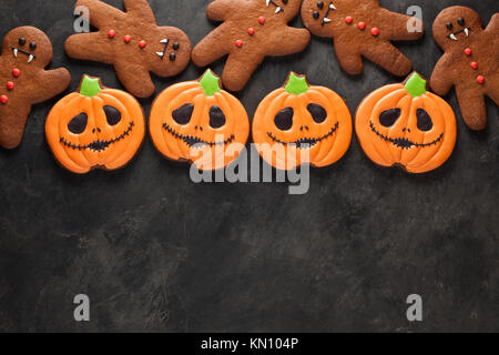 Gingerbread cookies faits maison pour l'halloween sous la forme de citrouilles et les hommes de pain d'épice vampire sur fond de béton foncé avec copie espace. Vue d'en haut. Banque D'Images