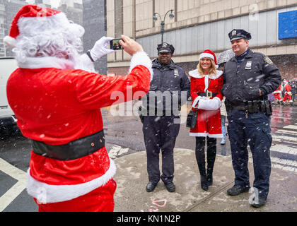 New York, États-Unis, 9 déc 2017. Une femme habillée en père Noël a sa photo prise par un autre Santa à côté de New York City Police garde la "fête" antacon foule qui se sont réunis au centre-ville malgré la tempête de neige. Photo par Enrique Shore/Alamy Live News Banque D'Images