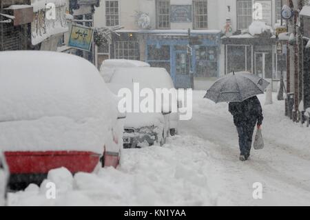 Kington, England, UK. Déc 10, 2017. Une femme utilise un parapluie pour protéger sa voiture de la neige qu'elle porte ses courses jusqu'Kington, rue Church, Kington, Herefordshire, Angleterre. Crédit : Andrew Compton/Alamy Live News Banque D'Images