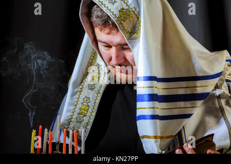 Des bougies juive allumant des bougies à la main des hommes dans la menorah sur table servi pour Hanoukka Banque D'Images